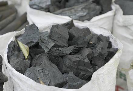 Close-up of anthracite coal pieces and a bag of coal fuel