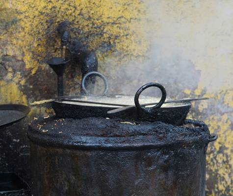 A homeowner emptying a coal stove ash pan into a metal container outdoors