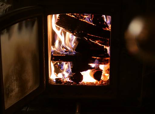 A gas stove insert installed in a brick fireplace, showing venting system