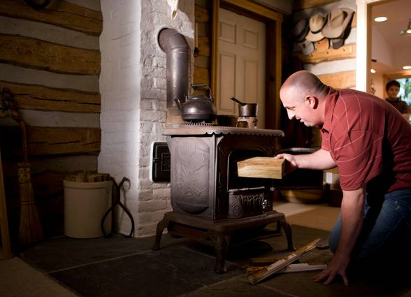 A professional inspecting and troubleshooting a heating stove in a home