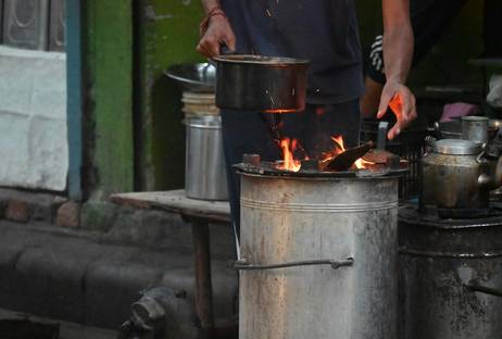 A person adding coal and shaking grates on a hand-fired coal stove