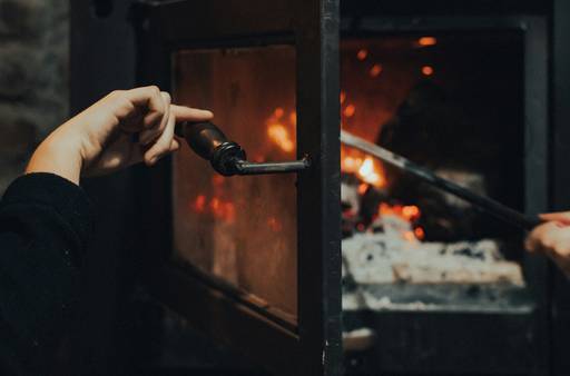 Close-up of a hand operating a gas stove with a remote