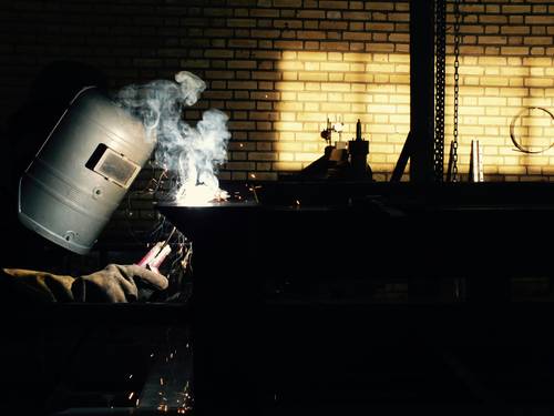 A technician vacuuming ash from a pellet stove burn pot and inspecting the fan