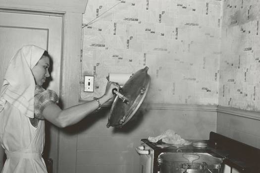 A person refilling the hopper and setting controls on a pellet stove