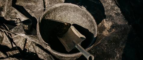 Close-up of gloves, mask, and metal ash bucket for stove cleaning safety