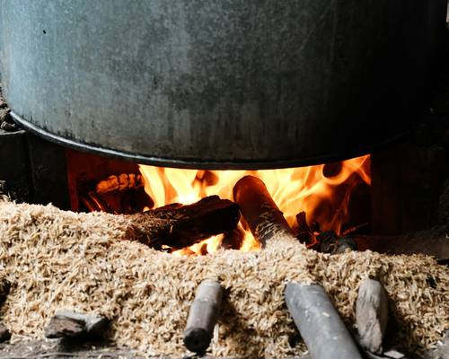 A selection of different stove fuels: firewood, pellet bags, gas tank, coal, electric cord