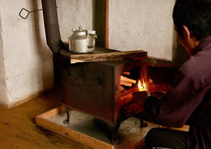 A homeowner performing routine maintenance on a heating stove