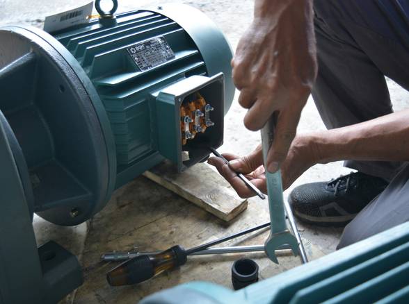 A certified technician troubleshooting a home heating stove, tools in hand